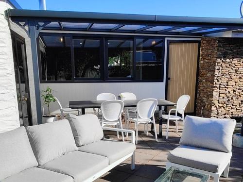 a patio with white couches and a table and chairs at Holiday retreat in the heart of old Cromwell! in Cromwell