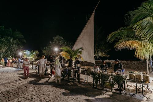 Un groupe de personnes debout autour de tables sur la plage la nuit dans l'établissement LUX Marijani Zanzibar, à Pwani Mchangani