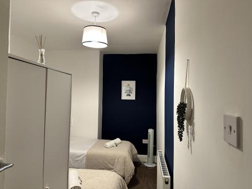 Un dormitorio con 2 camas y una pared de acento azul en Charming Apartment Near Broad Green Hospital, en Liverpool