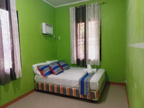 - une chambre avec des murs verts et un lit avec des oreillers dans l'établissement Samal Island Garden Villa - Spacious 3BR, AC, Wi-Fi, Indoor-Outdoor Kitchens, à Caliclic