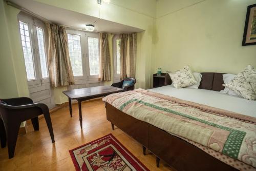 a bedroom with a bed and a desk and windows at The Golden Sunrise Hotel in Nainital