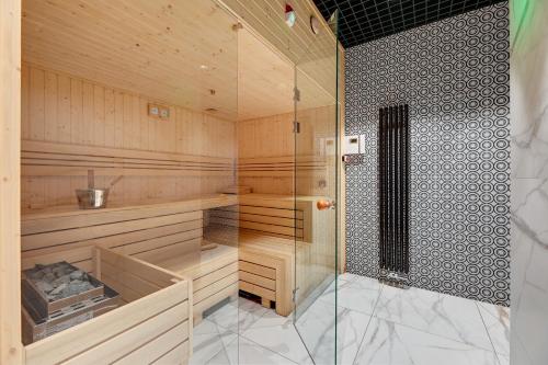 a sauna with wooden walls and a glass shower at Nadmotławie Deluxe 1 Sauna & Siłownia by Grand Apartments in Gdańsk