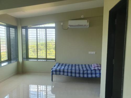 una camera con un letto in una stanza con finestre di Samarth Homestay a Ratnagiri