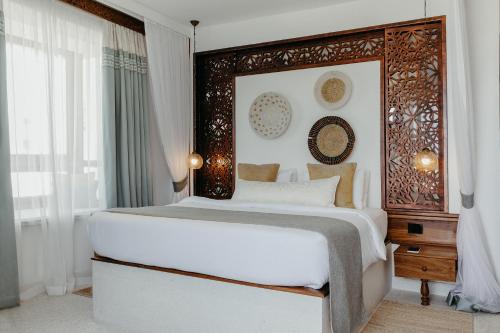 a bedroom with a large bed with a wooden headboard at LUX* Marijani Zanzibar in Pwani Mchangani