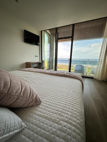 a bedroom with a bed with a view of the ocean at Hotel A Ladela in O Vicedo