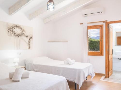 two beds in a white room with a window at Can Colet by Sunvillas Mallorca in Pollença