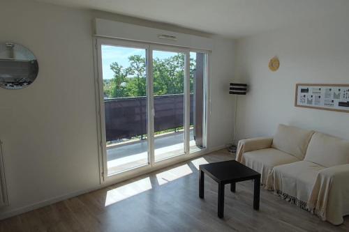 a living room with a couch and a large window at Appartement type T2 proche commodités et gare avec accès direct paris in Éragny