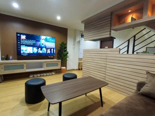 a living room with a table and a large tv at BG Bed Hometel Hat-Yai Songkhla in Hat Yai
