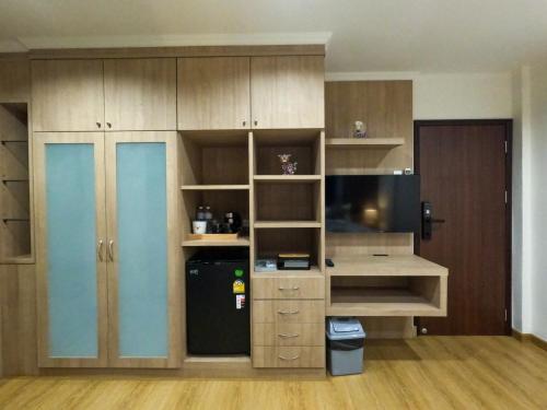 a kitchen with wooden cabinets and a black refrigerator at BG Bed Hometel Hat-Yai Songkhla in Hat Yai