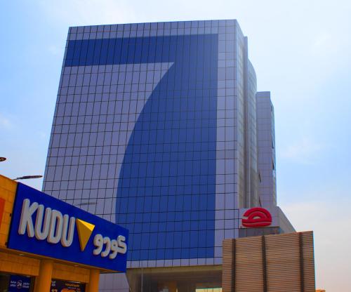 a tall glass building with a kydex sign in front at SAMT INN HOTEL فندق سمت إن in Riyadh