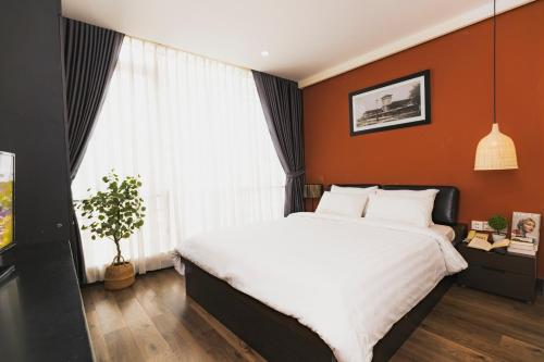 a bedroom with a large bed with orange walls at The One Premium Hotel in Ho Chi Minh City