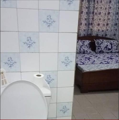 a bathroom with a toilet and a tiled wall at Résidences Lili in Douala