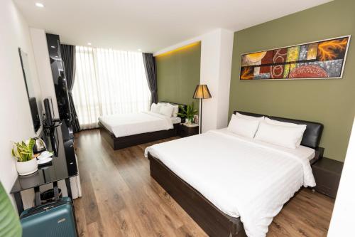 a hotel room with two beds and a television at The One Premium Hotel in Ho Chi Minh City