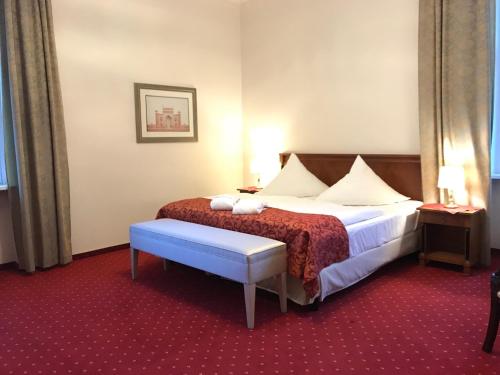 a hotel room with a bed and a bench at Hotel Prinzenpalais Bad Doberan in Bad Doberan