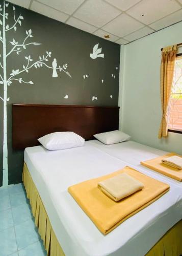 a bed with white sheets and birds on the wall at Phang Nga Guesthouse in Phangnga