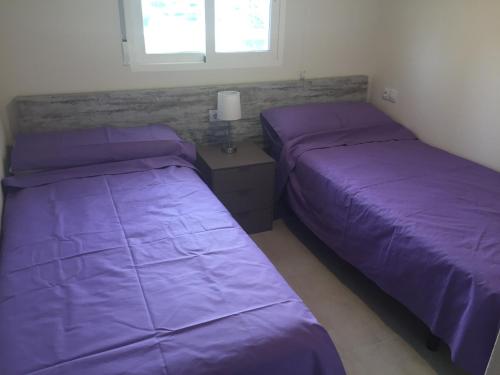 La HoradadaにあるVista Azul 3027 close to the beach, heated pool in winterの紫のシーツが備わる客室内のベッド2台