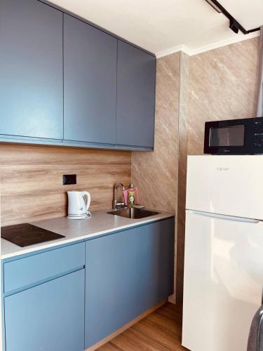 a kitchen with blue cabinets and a sink and a refrigerator at C Tower Premium Apartments, Panoramic Sea View in Netanya