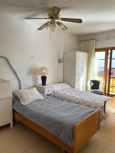 een slaapkamer met 2 bedden en een plafondventilator bij Atlantic View Apartment Los Cristianos At Marysol Hotel Tenerife in Arona