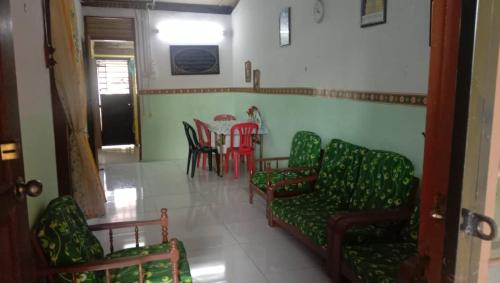 une salle à manger avec des chaises vertes, une table, une table et des chaises dans l'établissement Homestay Hajah Zainab Linggi Negeri Sembilan, 