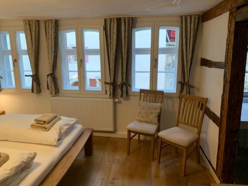 a bedroom with two chairs and a bed and windows at Gästehaus am Plönlein in Rothenburg ob der Tauber