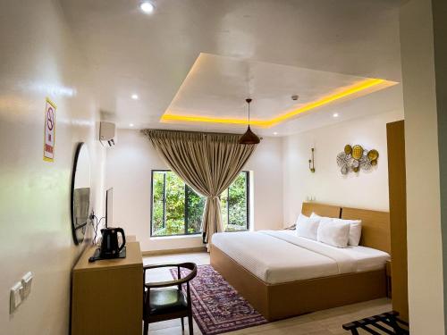 Schlafzimmer mit einem Bett, einem Schreibtisch und einem Fenster in der Unterkunft Address hotels and towers in Abuja
