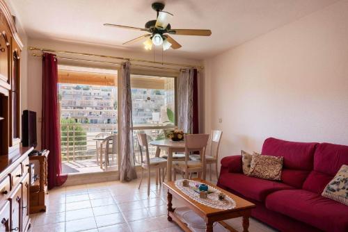 ein Wohnzimmer mit einem roten Sofa und einem Tisch in der Unterkunft Apartamento Zeus 4 - PlusHolidays in Calpe
