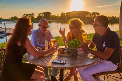 un grupo de personas sentadas alrededor de una mesa con bebidas en Parc Maasresidence Thorn Lake View Hotel Rooms en Thorn