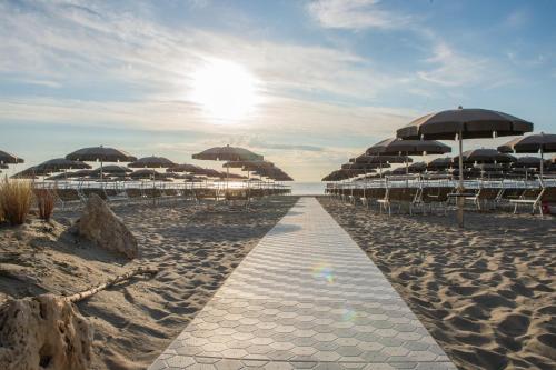 a sandy beach with umbrellas and chairs and the ocean at Hotel Majestic in Milano Marittima