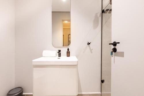 a white bathroom with a sink and a mirror at The Tyne Luxury Apartments in Durban