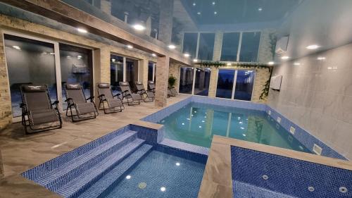 a swimming pool in a building with chairs around it at SPA hotel Villa Sofia in Yablunytsya
