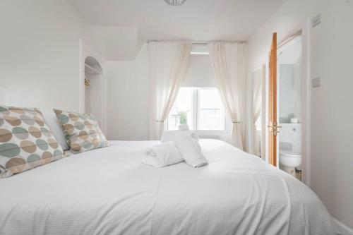 a white bed in a white room with a window at Park Place Elie, Perfect for the beach in Elie