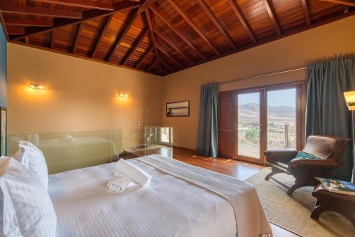 1 dormitorio con 1 cama, 1 silla y 1 ventana en Villa Atlanntes con piscina en Fuerteventura, en Triquivijate