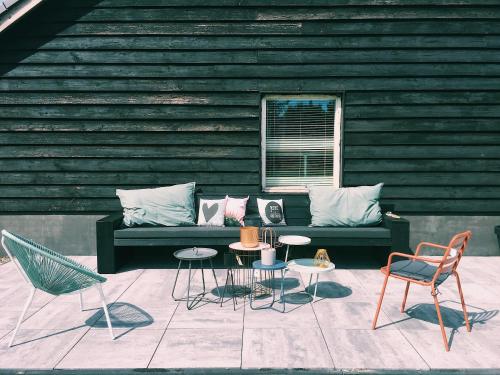 a green couch with chairs and tables in front of a building at De Appelhoeve in Terschuur