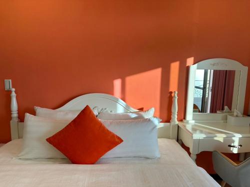 a bedroom with a white bed with an orange wall at Bei Ao Bi Shan Jyu in Dongyin