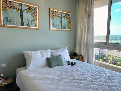 um quarto com uma grande cama branca e uma janela em דירה עם נוף לים בנאות גולף בריכה , ספא , חדר כושר em Caesarea