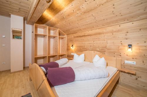 a large bed in a room with a wooden wall at Ferienhäuser Tschofen Garfrescha in Sankt Gallenkirch