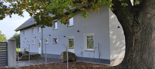 Una casa blanca con un árbol delante. en Kleine Auszeit 1, en Forst