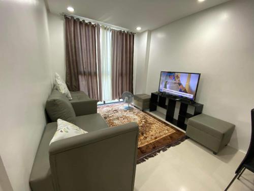 sala de estar con sofá y TV de pantalla plana en Room 703 Pontefino Hotel, en Batangas