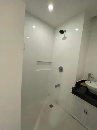 y baño blanco con lavabo y ducha. en Room 703 Pontefino Hotel, en Batangas