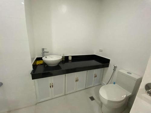 a white bathroom with a sink and a toilet at Room 703 Pontefino Hotel in Batangas City