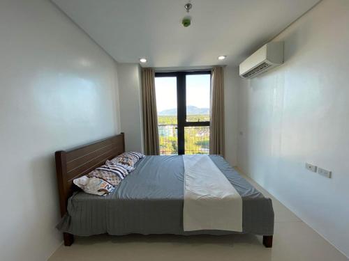 a bedroom with a bed with a large window at Room 703 Pontefino Hotel in Batangas City
