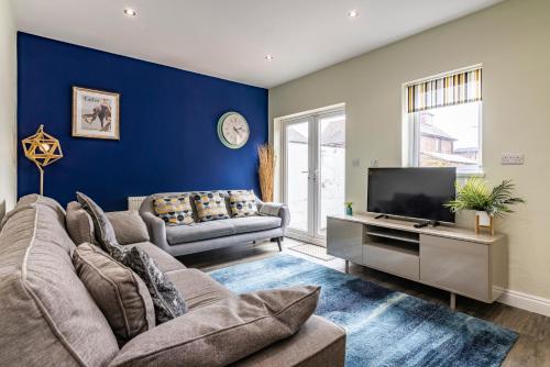 4 Bed Terraced House in Beeston with Convenient City Centre Access في نوتينغهام: غرفة معيشة مع أريكة وتلفزيون