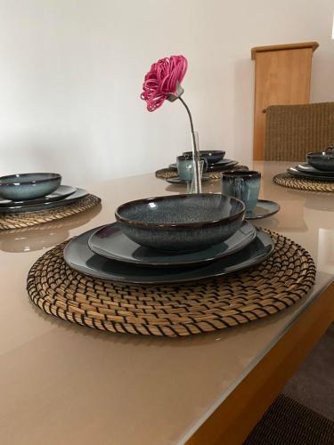 a table with black plates and a flower in a vase at Ferienwohnung Flussufer No.12 in Schweich