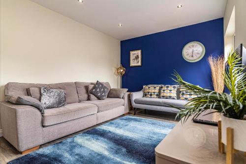 uma sala de estar com um sofá e uma parede azul em 4 Bed Terraced House in Beeston with Convenient City Centre Access em Nottingham