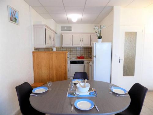 une cuisine avec une table avec des chaises et un réfrigérateur dans l'établissement Saint Georges de Didonne - APPARTEMENT rez-de-chaussée - mode TOUT à PIED, à Saint-Georges-de-Didonne