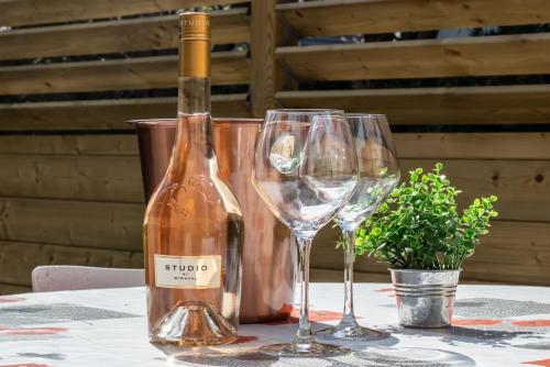 une bouteille de vin et deux verres à vin sur une table dans l'établissement Notting Hill duplex au calme 5 min du lac, à Annecy