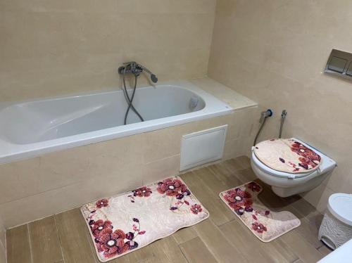a bathroom with a tub and a toilet and mats at Appartement Les Pergolas in Ariana