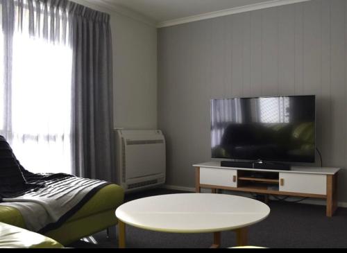 - un salon avec une télévision, un canapé et une table dans l'établissement Inspire Boutique Apartments, à Devonport