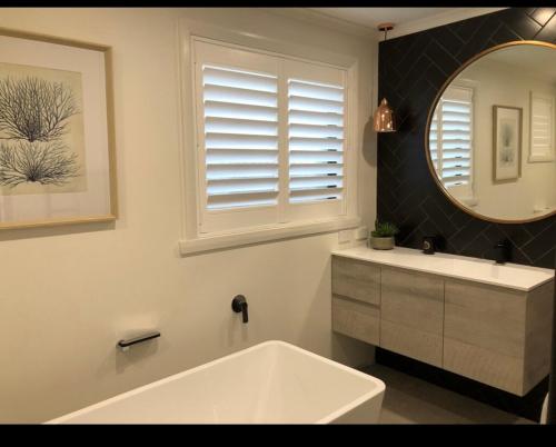 a bathroom with a tub and a sink and a mirror at Inspire Boutique Apartments in Devonport