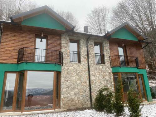 ein Steinhaus mit großen Fenstern im Schnee in der Unterkunft Villa Gjelbër in Prizren